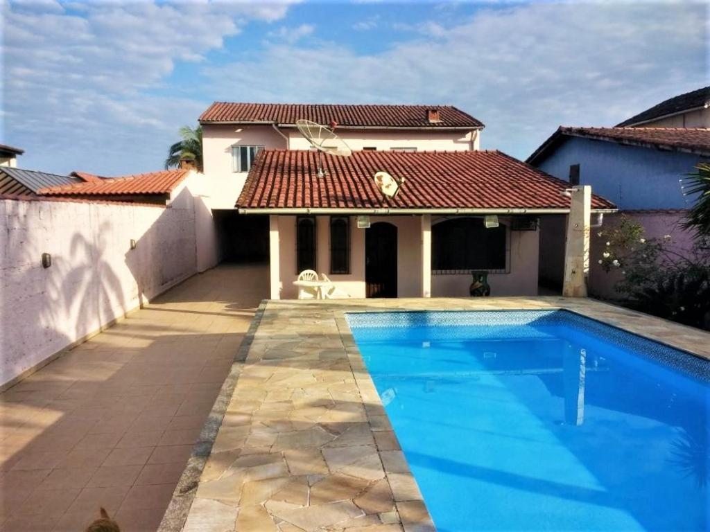 eine Villa mit einem Pool vor einem Haus in der Unterkunft Casa com piscina in Bertioga