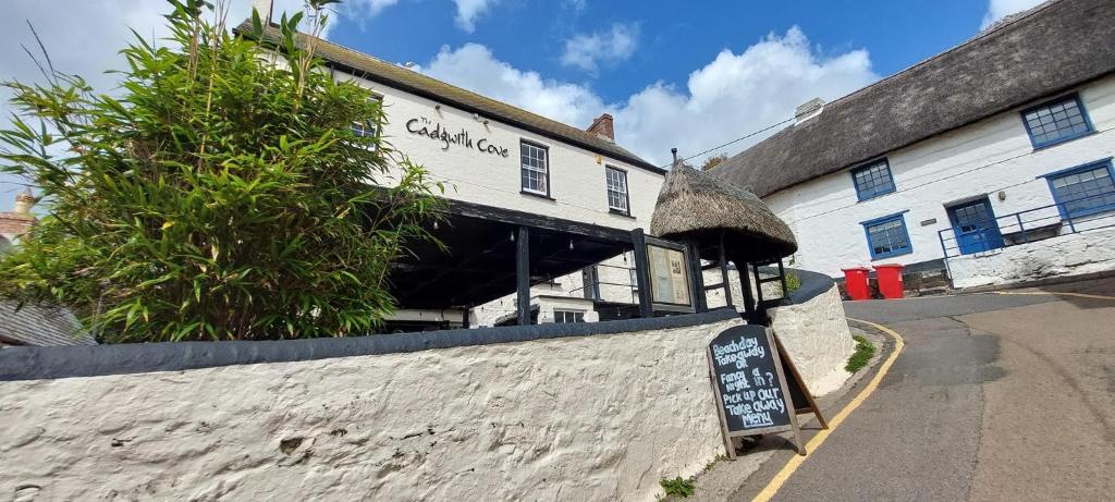 een wit gebouw met een bord ervoor bij Cadgwith Cove Inn in Cadgwith