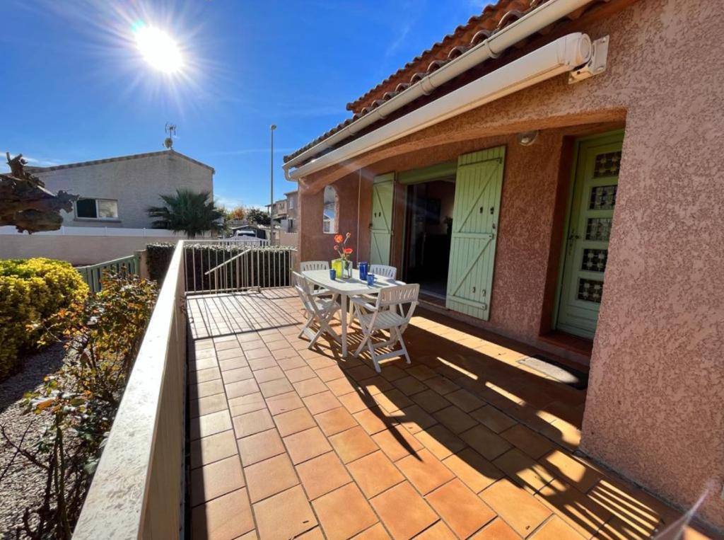 une terrasse avec une table et des chaises dans une maison dans l'établissement Will, à Valras-Plage