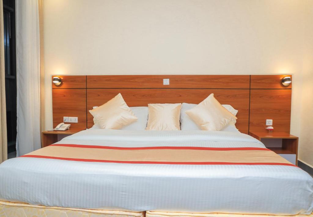 een slaapkamer met een groot bed met een houten hoofdeinde bij Standard Single Room At Amikus Hotel in Gasanze