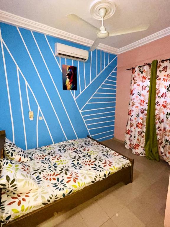 1 dormitorio con 1 cama con pared azul en Fredy meublé, en Ouagadougou