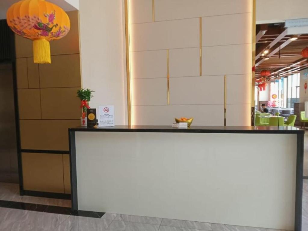 A compact reception counter beside a decorated hotel lobby and dining area.