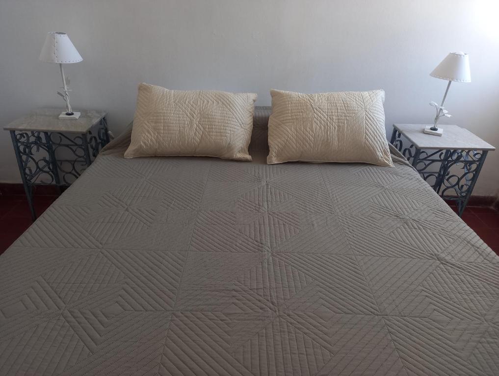 a bed with two pillows on it with two tables at Casa Eusebio - Catamarca capital in San Fernando del Valle de Catamarca