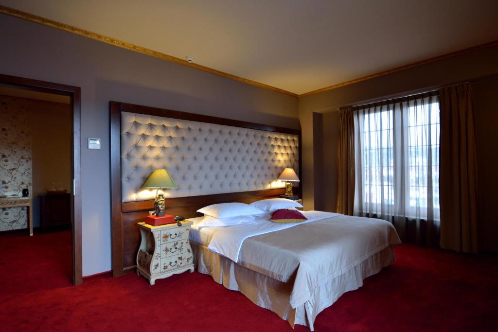 ein Hotelzimmer mit einem großen Bett und einem Fenster in der Unterkunft Simfonia Boutique Hotel in Râmnicu Vâlcea