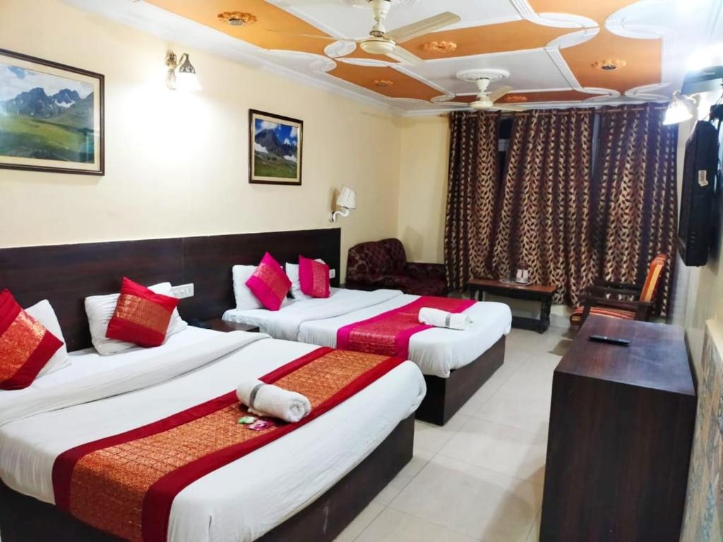 um quarto de hotel com duas camas com almofadas vermelhas em Hotel Star of Kashmir em Srinagar