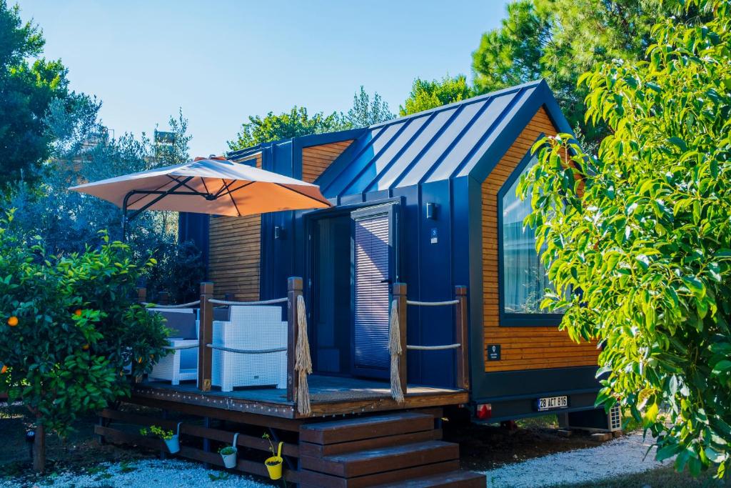 a blue tiny house with an umbrella and chairs at Efe Tiny House in Serik