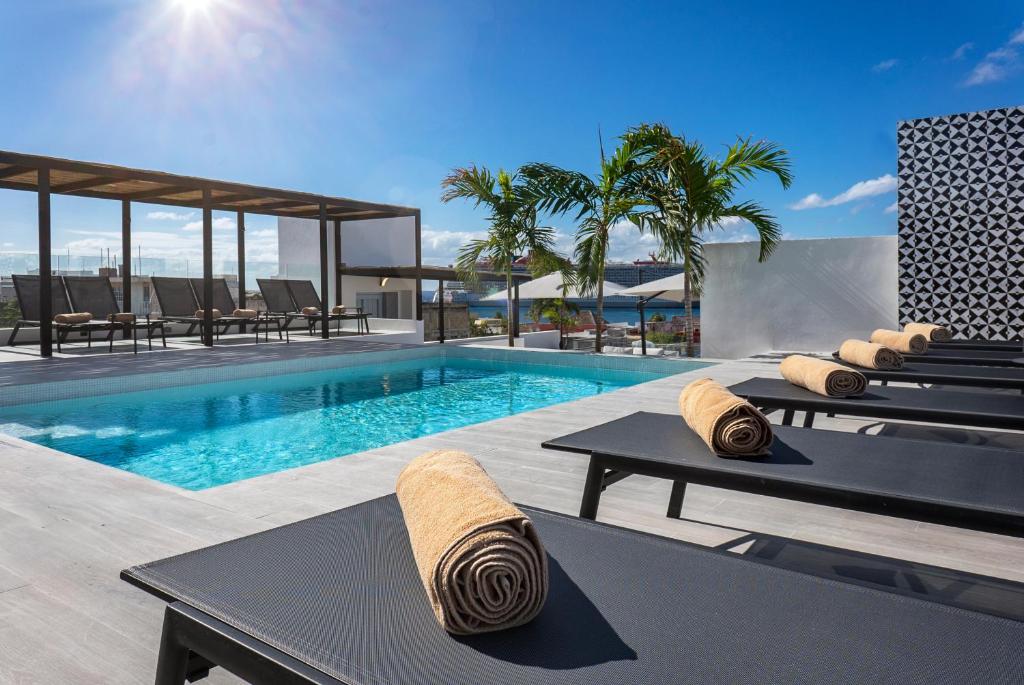 a swimming pool with tables and chairs next to a house at Coralia Boutique Hotel Cozumel in Cozumel