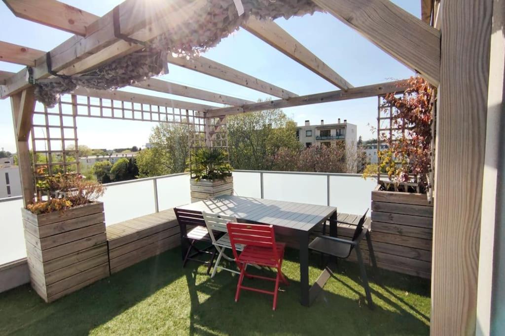 a patio with a table and chairs on a roof at Le Nid : Rooftop moderne surplombant la ville in Nantes
