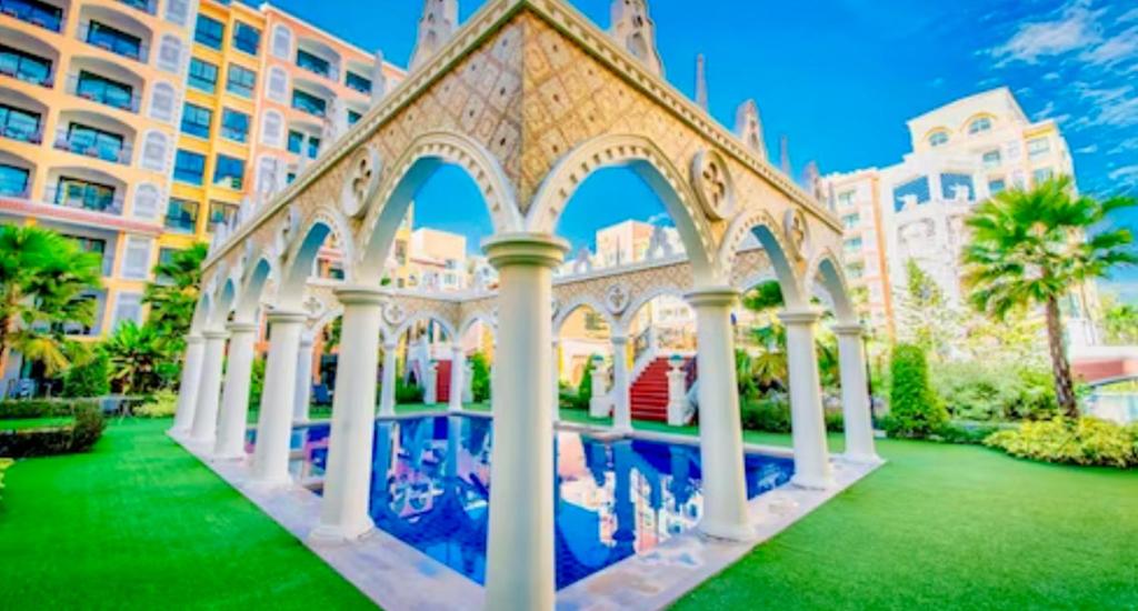 ジョムティエンビーチにあるLuxury stay Venetian signatureの柱のある建物、プール付きの緑の庭