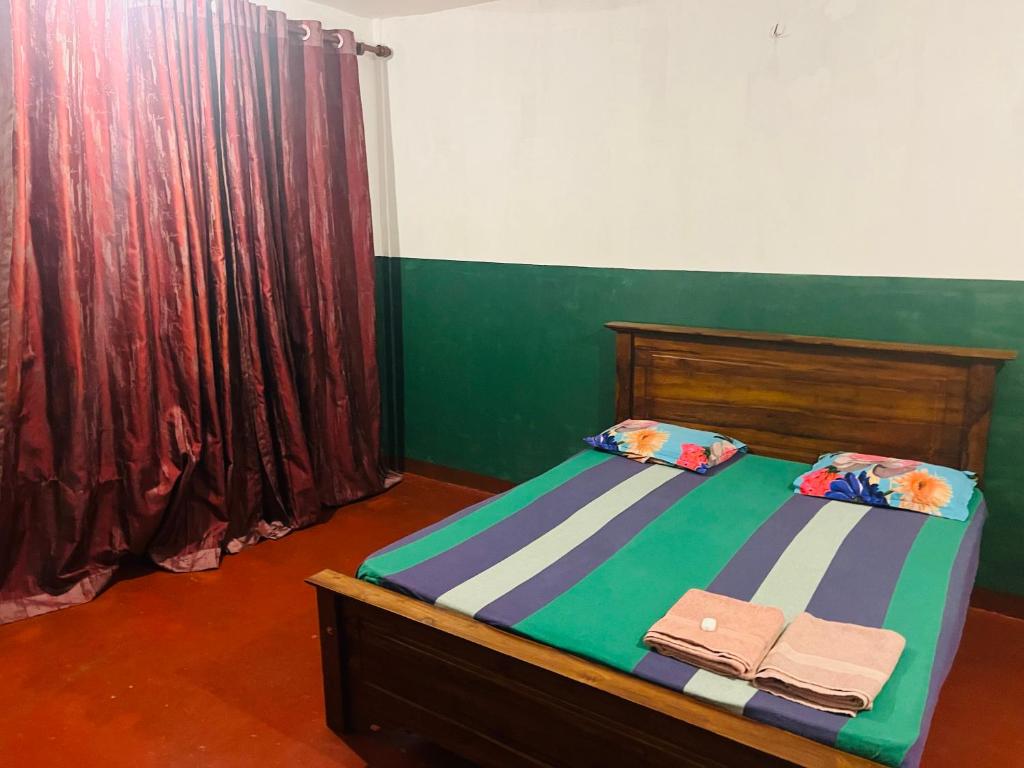 1 dormitorio con 1 cama con cortina verde y roja en Sahas Guest House en Boralesgamuwa