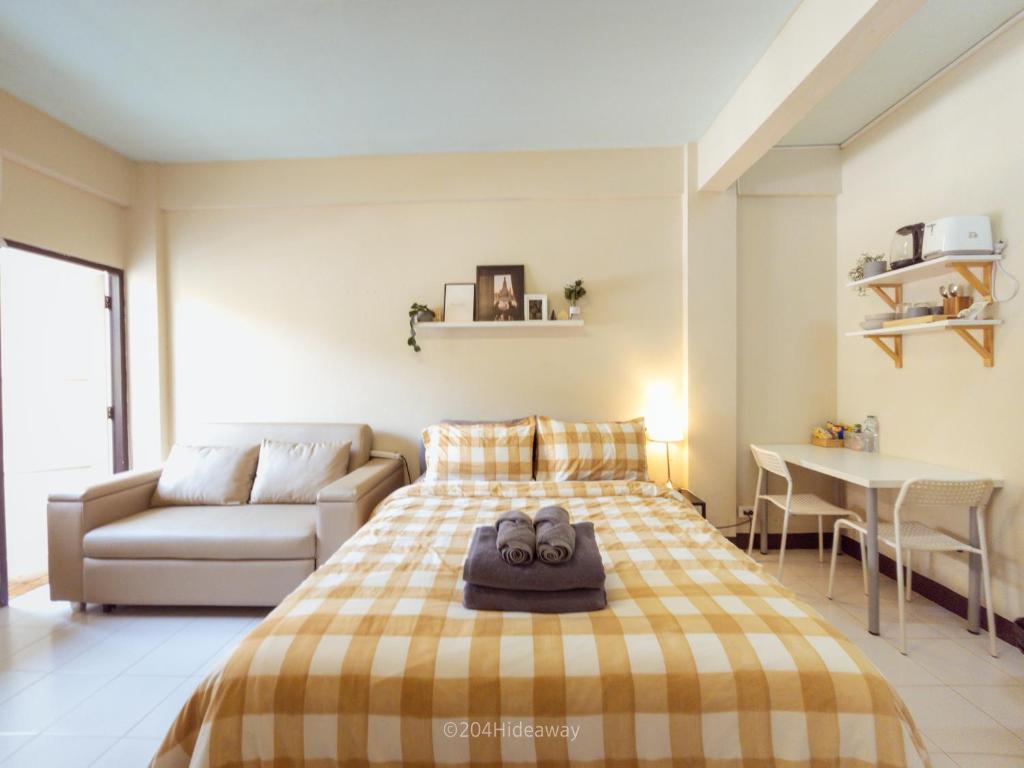 Hotel 204hideaway-Local Room with Street Food only 15 min walk to Skytrain, a bedroom with a bed and a couch and a table at 204hideaway-Local Room with Street Food only 15 min walk to Skytrain in Bangkok