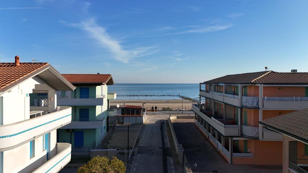 een uitzicht op het strand tussen twee gebouwen bij F001 - Fano, trilocale con portico a 30mt dal mare in Marotta