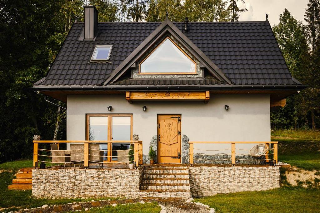 una pequeña casa blanca con techo negro en Leśne Zacisze, en Nowy Targ