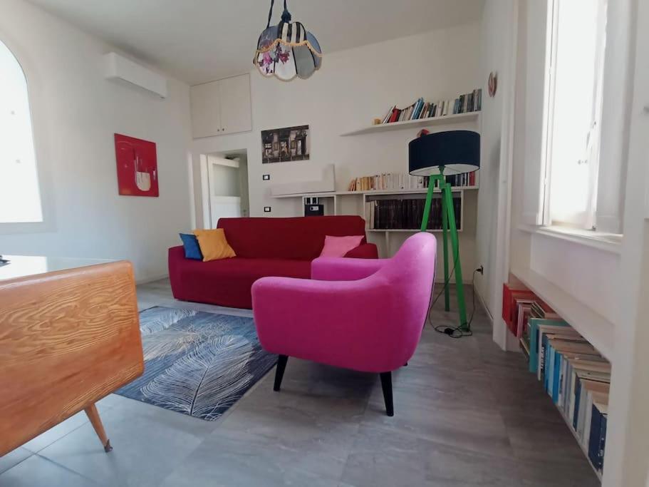 - un salon avec un canapé rouge et une chaise rose dans l'établissement L'Appartamento Storico dal Design Moderno, à Faenza