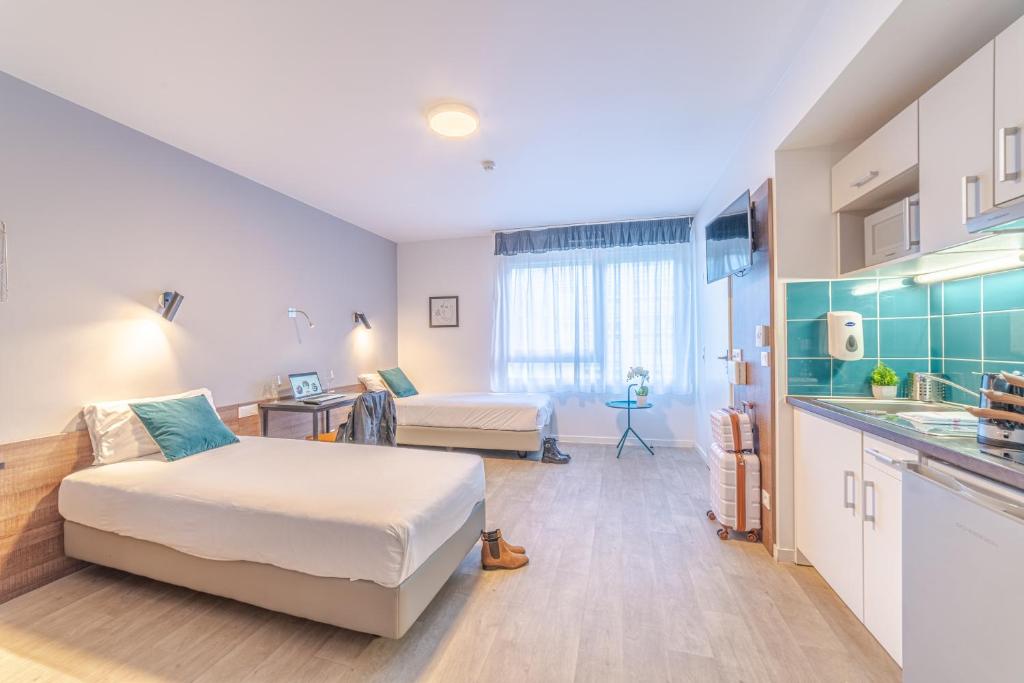 a large room with two beds and a kitchen at Break & Home Paris Italie Porte de Choisy in Ivry-sur-Seine