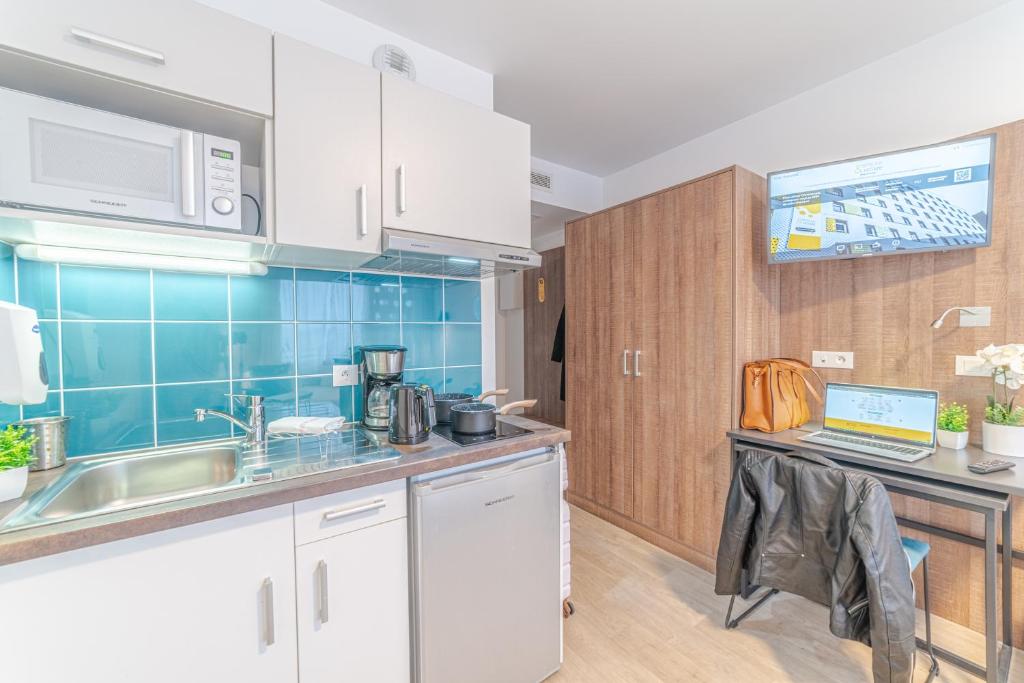 a kitchen with white cabinets and a laptop on a counter at Break & Home Paris Italie Porte de Choisy in Ivry-sur-Seine