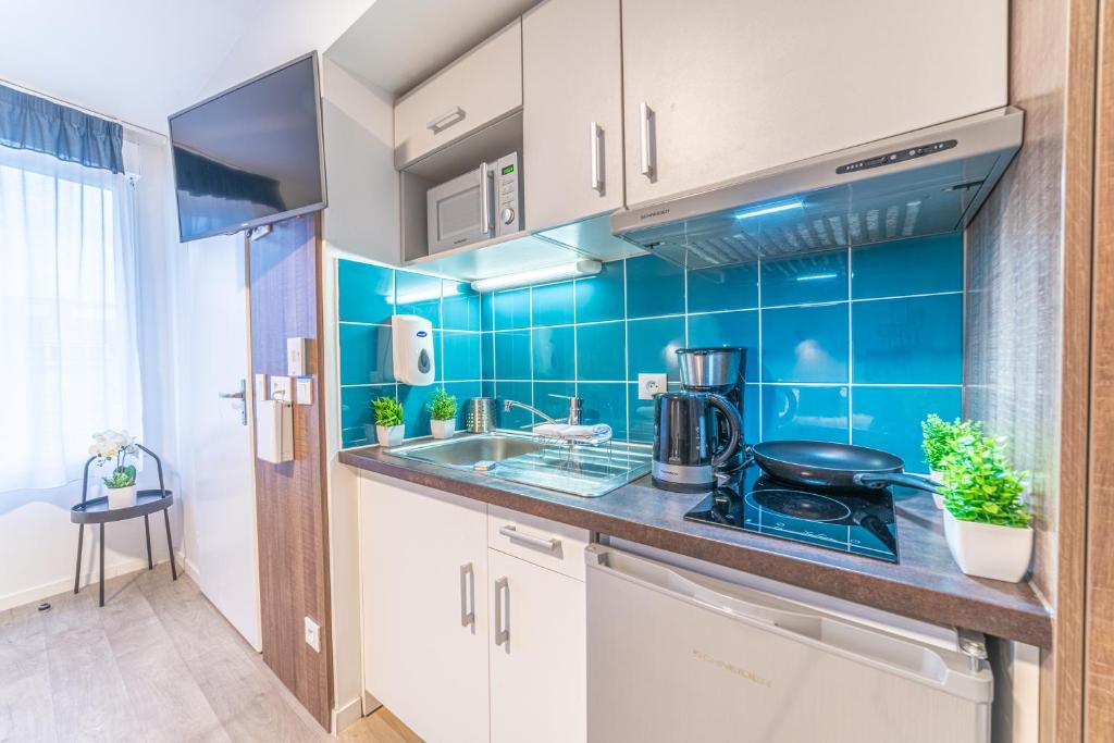 a kitchen with blue tiles on the wall at Break &amp; Home Paris Italie Porte de Choisy in Ivry-sur-Seine