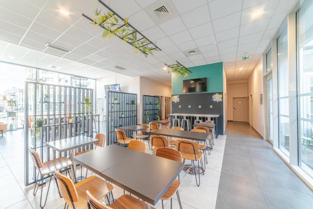 a cafeteria with tables and chairs and windows at Break &amp; Home Paris Italie Porte de Choisy in Ivry-sur-Seine