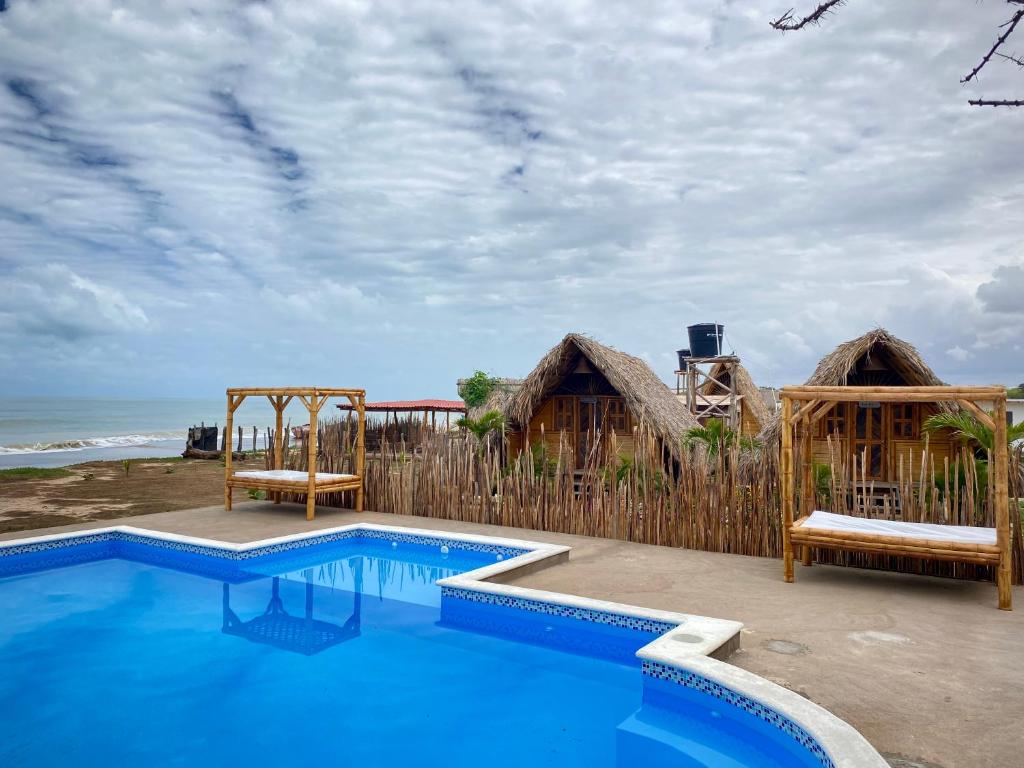 a swimming pool next to a wooden fence and the ocean at Guajira Beach in Ríohacha