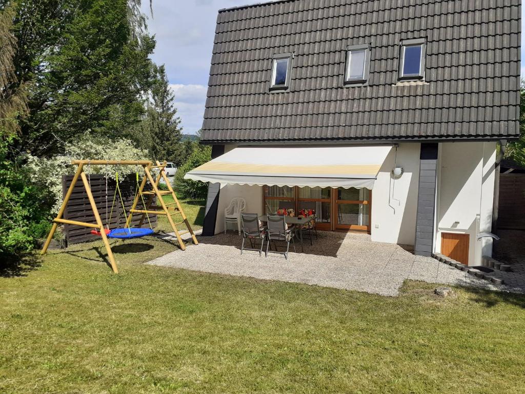 uma casa com uma tenda e um baloiço em Ferienhaus am See Lichtenberg Bayern Frankenwaldsee em Lichtenberg