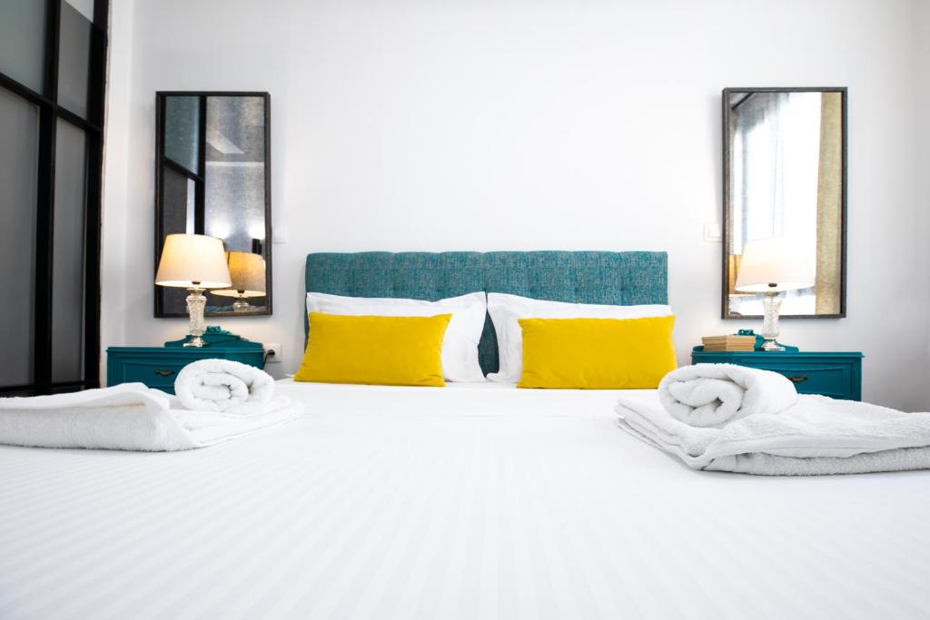 een slaapkamer met een groot wit bed met gele kussens bij Vibrant Studio Close To Panepistimio Metro-Zaloggou str in Athene
