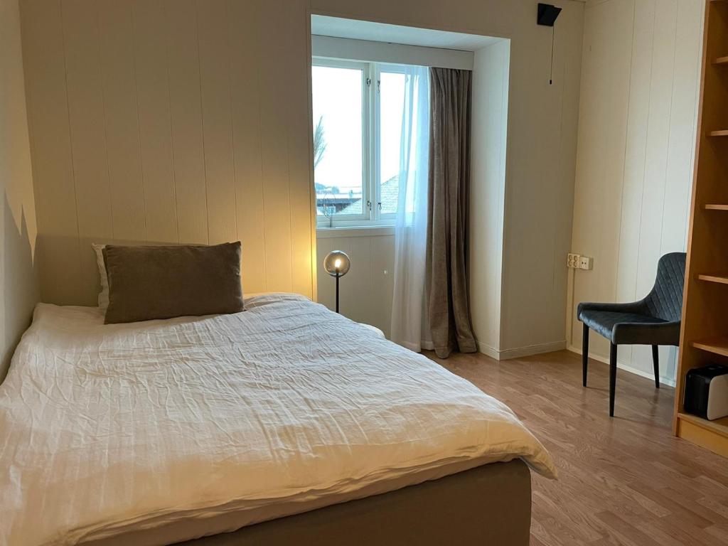 1 dormitorio con 1 cama con ventana y silla en Haugesund Urban Hotel en Haugesund