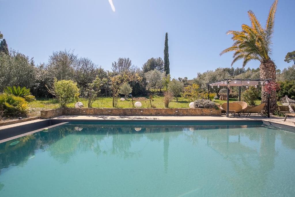 a swimming pool with blue water in a yard at Villa Des oliviers in Le Beausset