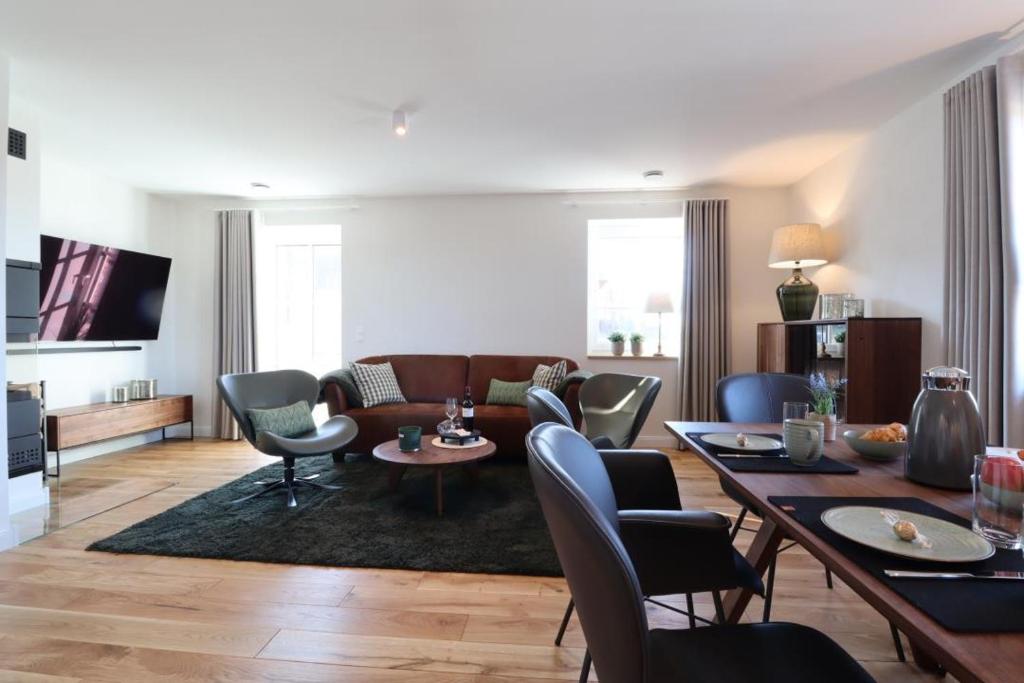 a living room with a couch and a table and chairs at Villa Heimathafen Rügen - Luxus gepaart mit Wellness in Lohme