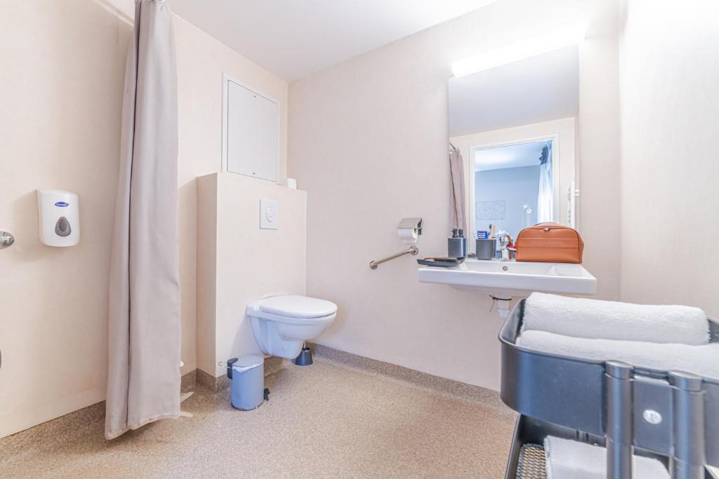 a white bathroom with a toilet and a sink at Break &amp; Home Paris Italie Porte de Choisy in Ivry-sur-Seine