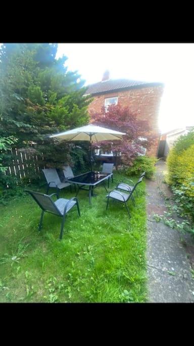 two chairs and a table with an umbrella in a yard at 2 bed full house with private summer garden in Elswick