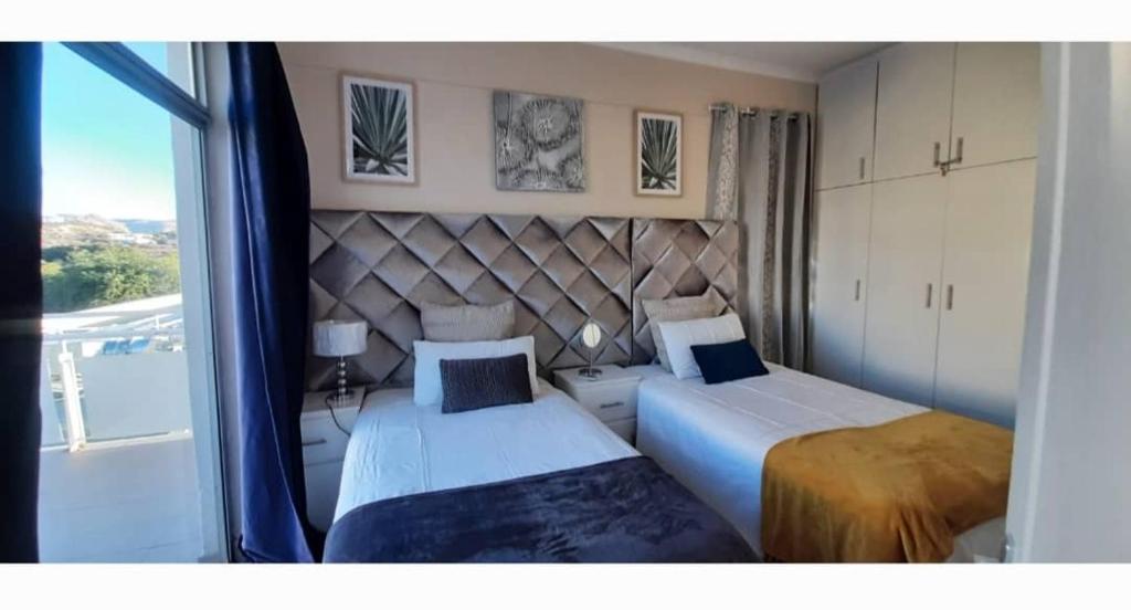 溫特和克的住宿－Maerua Mall Luxe Accommodations 3rd Floor，一间卧室设有两张床和大窗户