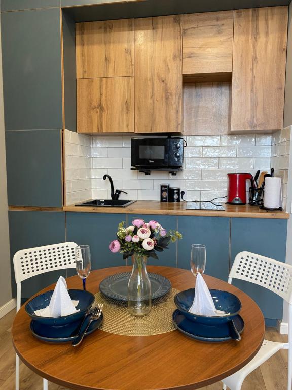 a wooden table with a vase of flowers on it at Новые апартаменты рядом с EXPO in Taldykolʼ