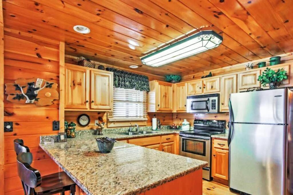 eine Küche mit einem Kühlschrank aus Edelstahl und Holzwänden in der Unterkunft Solid Ground Lodge with Yard! in Pigeon Forge