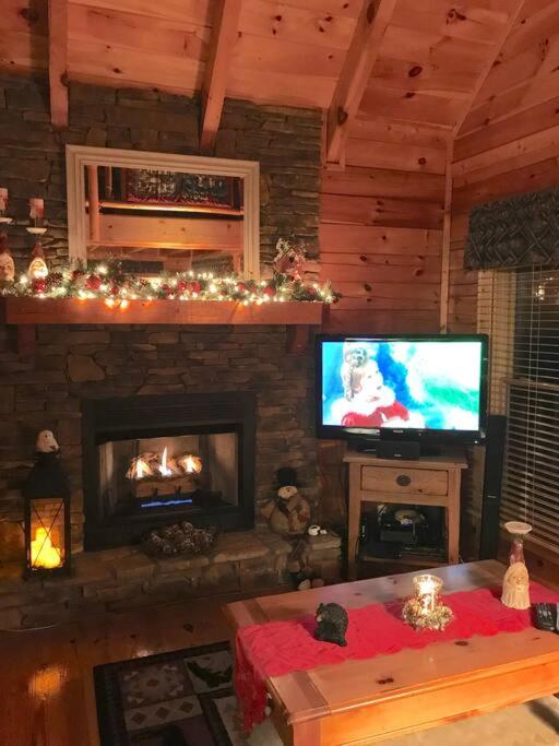 ein Wohnzimmer mit Kamin und Fernseher in der Unterkunft Solid Ground Lodge with Yard! in Pigeon Forge