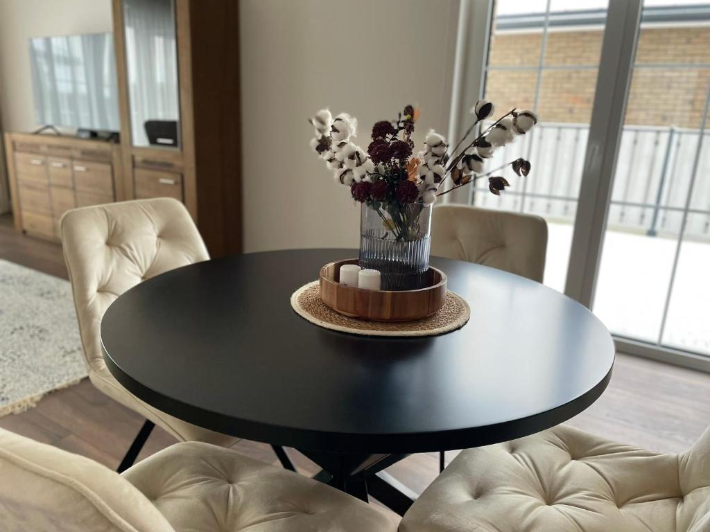 a black dining room table with a vase of flowers on it at MA apartments in Mažeikiai