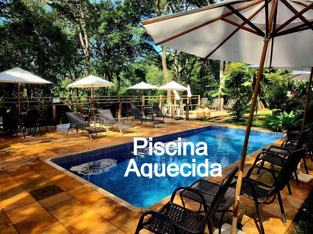 una piscina con sillas y sombrillas frente a un complejo en Pousada do Rodrigo en Macacos