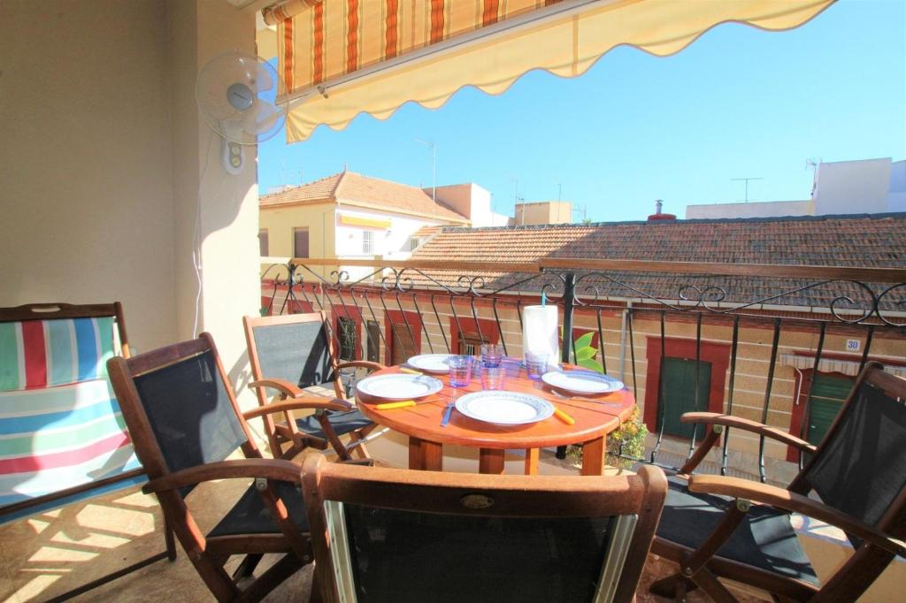 y balcón con mesa y sillas de madera. en Casa Meroño Los Alcazares, en Los Alcázares
