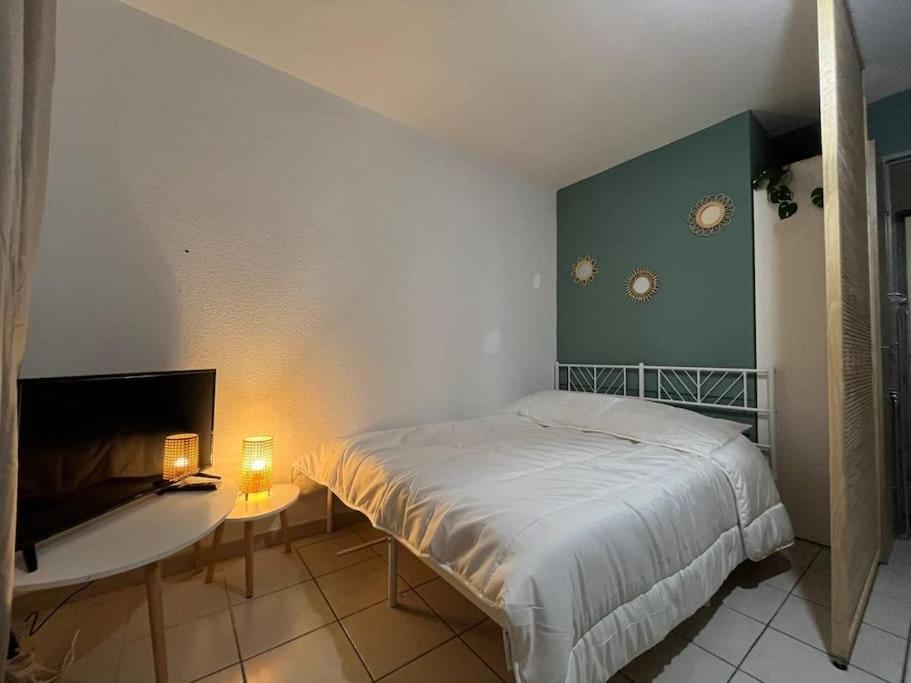 um quarto com uma cama e uma mesa com 2 candeeiros em Charmant Studio proche remparts et commerces em Avignon