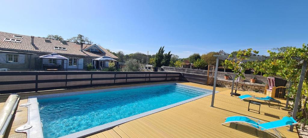 une piscine avec une terrasse en bois et une maison dans l'établissement Domaine des Prés de Joussac - Protocole sanitaire strict, à Jau-Dignac-et-Loirac