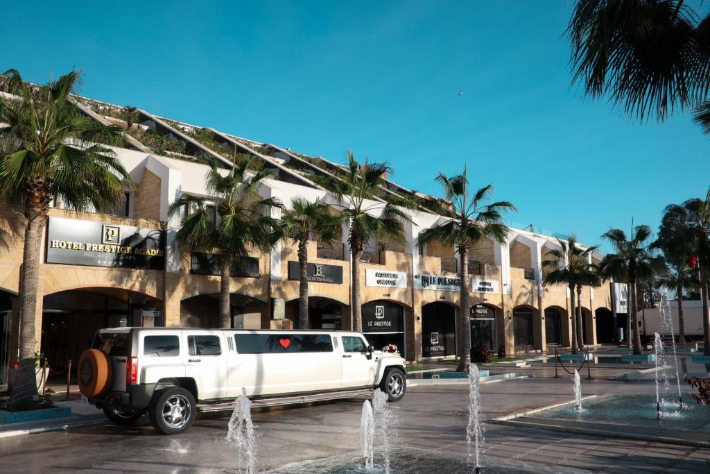 een witte truck geparkeerd voor een gebouw met palmbomen bij Hotel Prestige Agadir Boutique & SPA in Agadir