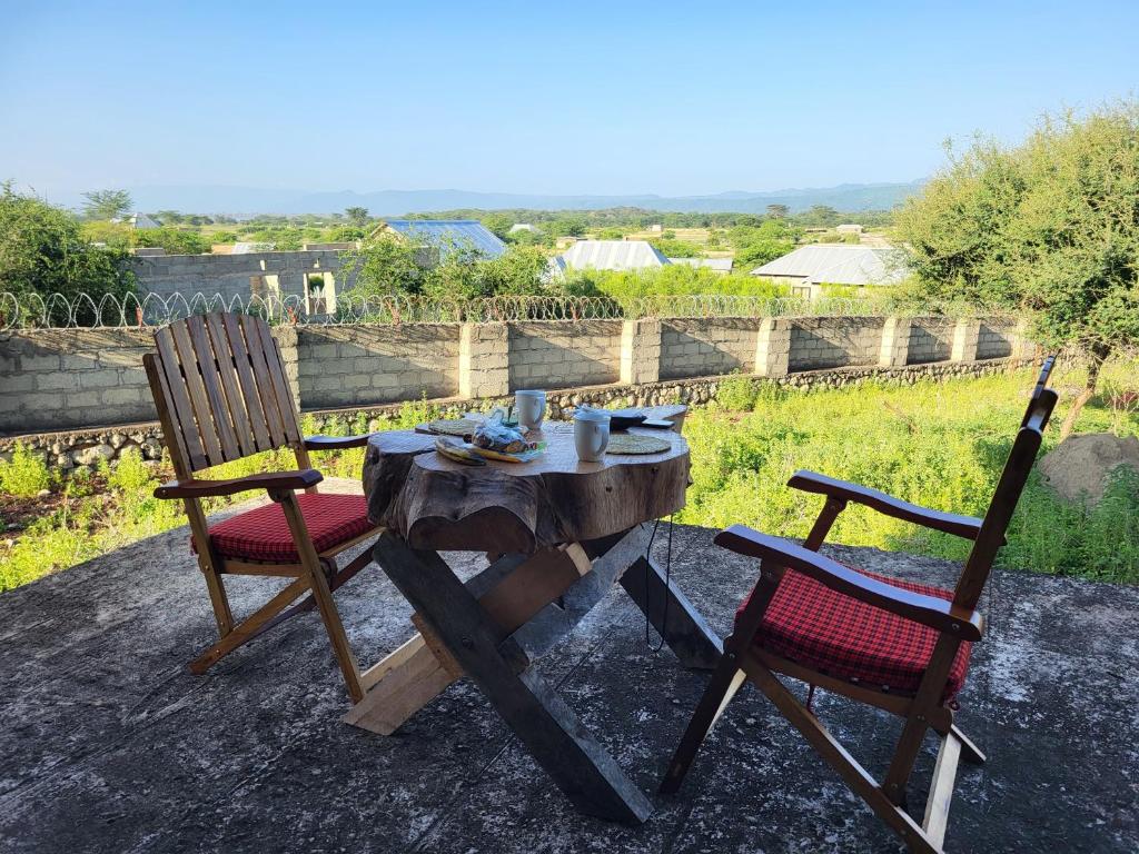 a wooden table and two chairs with a table and a table and chairs at Mwi Village House in Mto wa Mbu