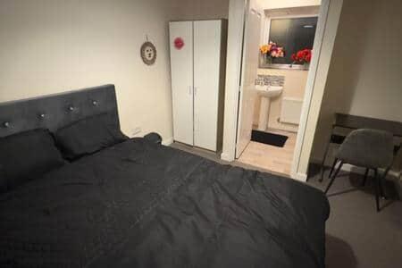 a bedroom with a black bed and a bathroom at Central Birmingham in Birmingham