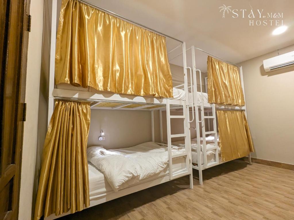 um quarto com 2 beliches com cortinas amarelas em STAY Hostel & Motorbike Rental - Thakhek em Thakhek