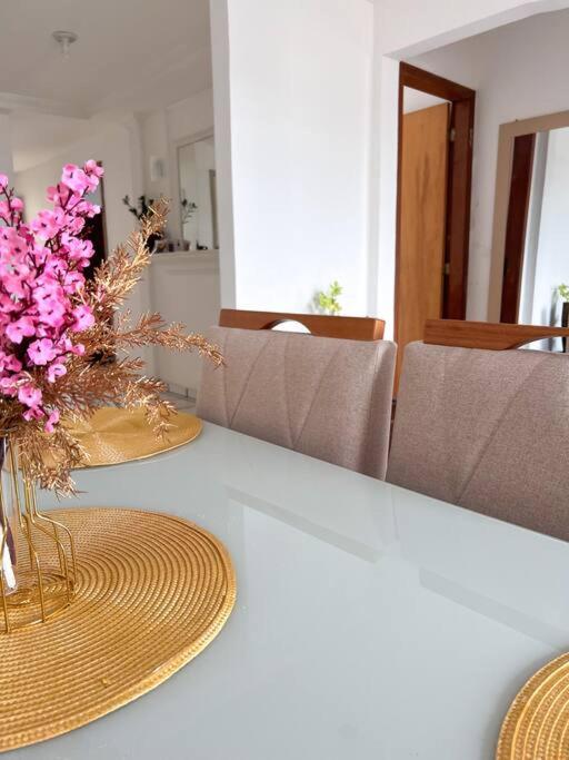 a table with two plates and a vase of flowers at Apartamento próximo da Praia in Vila Velha
