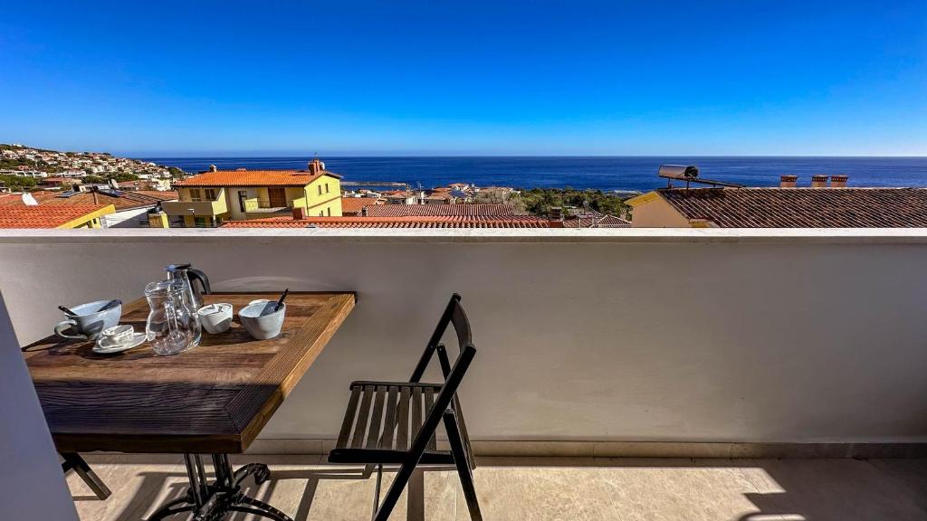 a table on a balcony with a view of the ocean at Casa Luna Blanca in Cala Gonone