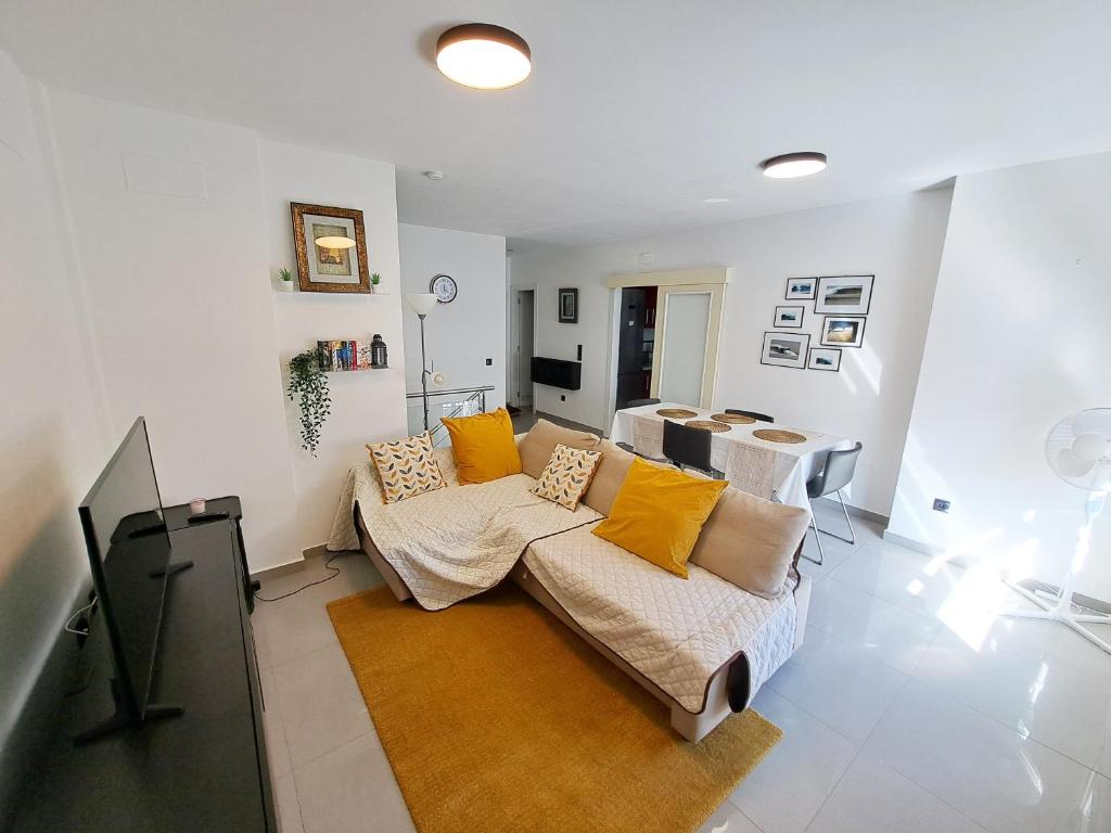 Hub Retreat Las Palmas في لاس بالماس دي غران كاناريا: غرفة معيشة مع أريكة ووسائد صفراء