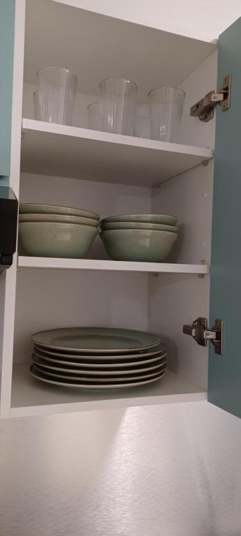 a kitchen cabinet with plates and bowls on shelves at NANA A33 Appartement 2 Chambres Climatisées cuisine équipée Netflix in Cayenne