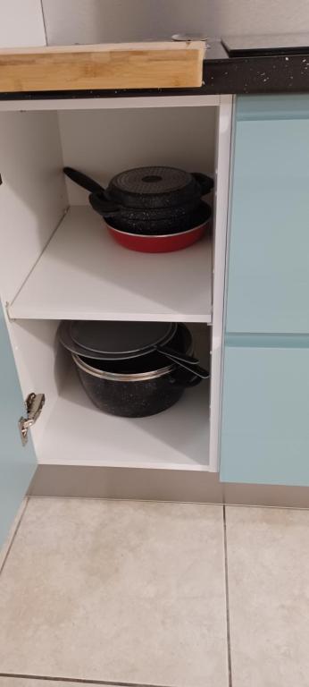 a cupboard with a pan and plates in it at NANA A33 Appartement 2 Chambres Climatisées cuisine équipée Netflix in Cayenne