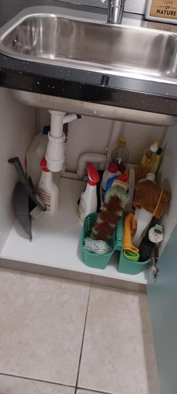 a shelf under a sink with dishes under a sink at NANA A33 Appartement 2 Chambres Climatisées cuisine équipée Netflix in Cayenne