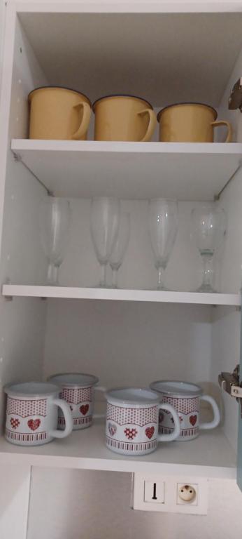 a white shelf with cups and dishes in a refrigerator at NANA A33 Appartement 2 Chambres Climatisées cuisine équipée Netflix in Cayenne